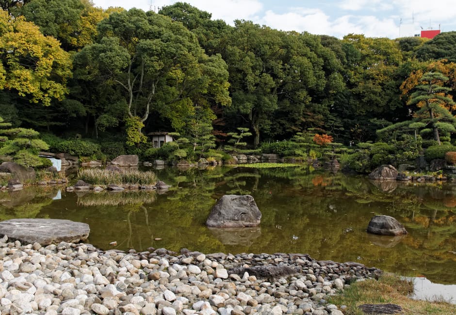 Pond with stones and trees in Keitakuen Garden in Osaka