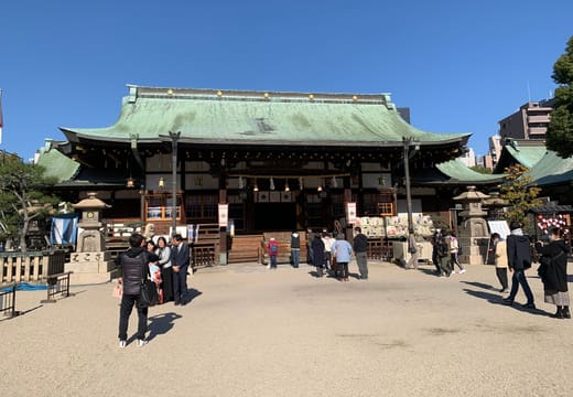Main hall of Osaka Tenmangu with its green copper roof and visitors in the courtyard