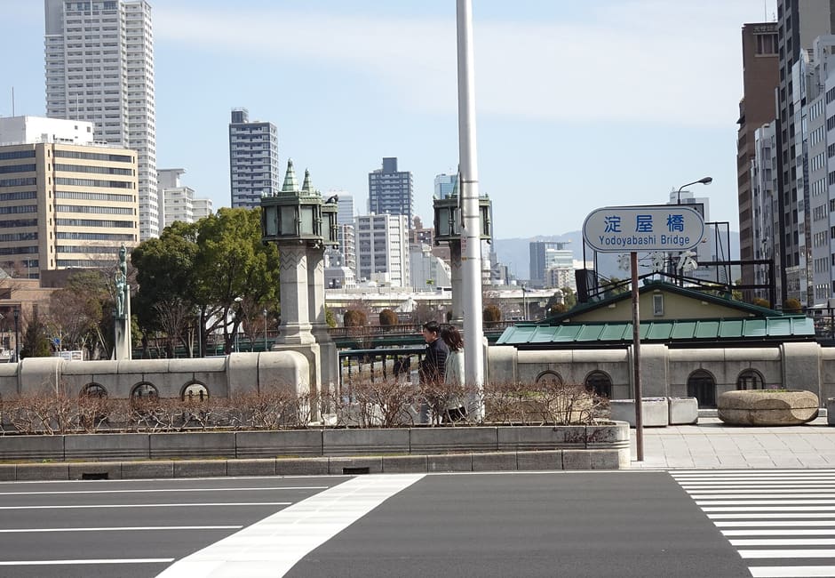Yodoyabashi Bridge with its stone lamp posts and name sign in central Osaka